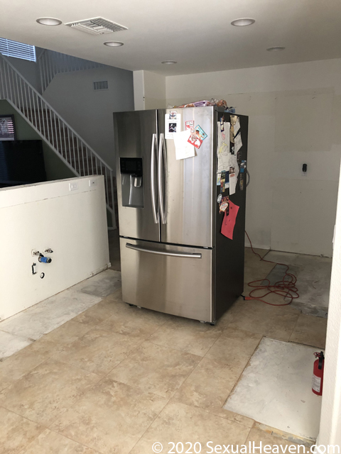 A kitchen with no cabinets and missing tile.