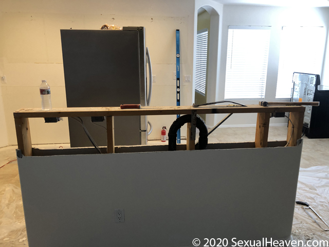 A kitchen island cut open with exposed plumbing.