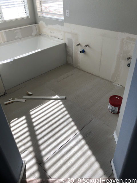 Cement board on the floor, drywall being repaired, and an installed tub.