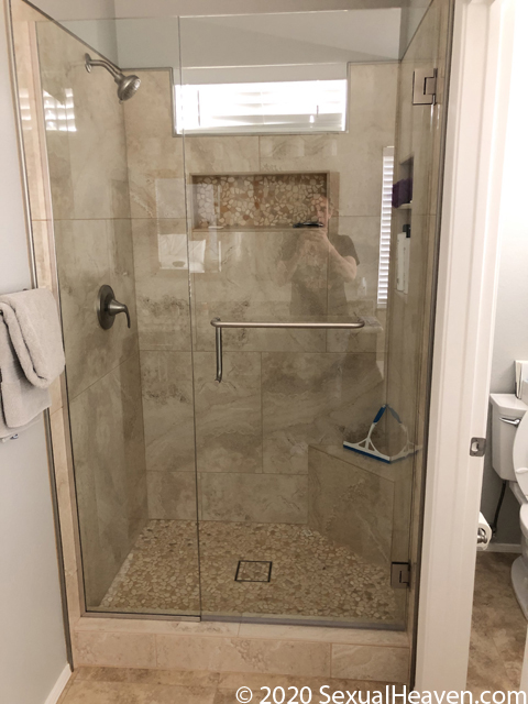 A custom tiled shower with a shower door installed.